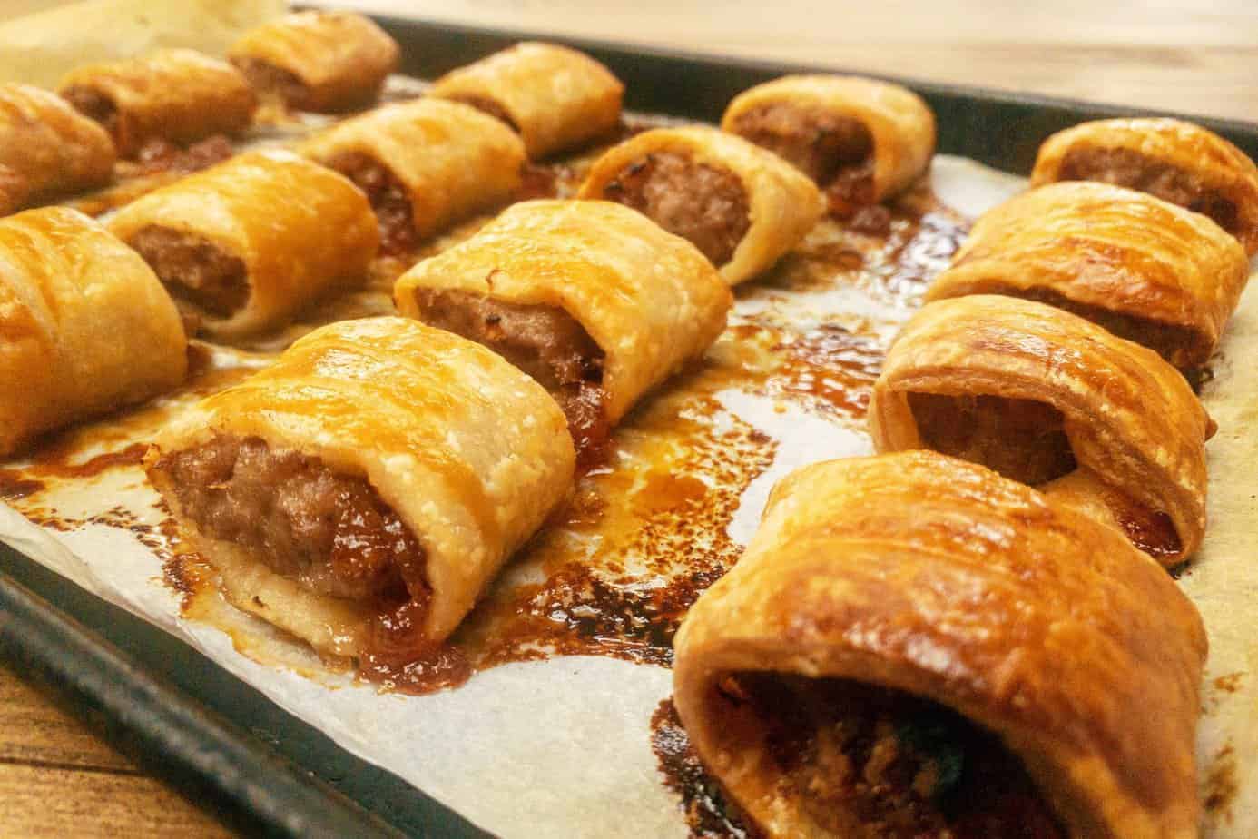 freshly cooked sausage rolls on a baking tray