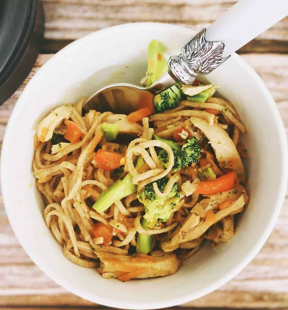 chicken and broccoli noodles in a bowl with spoon