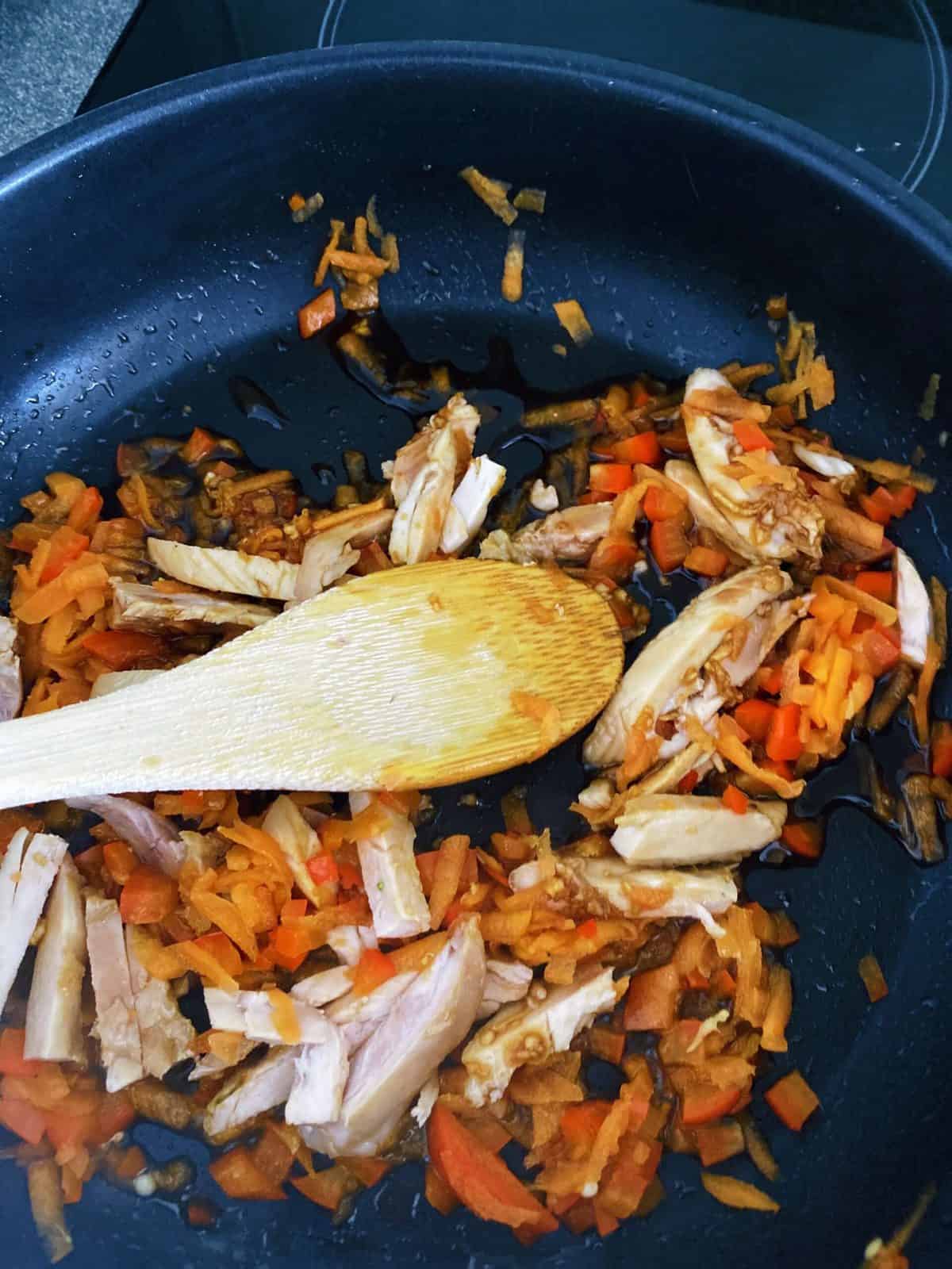 chicken and carrots cooking in pan