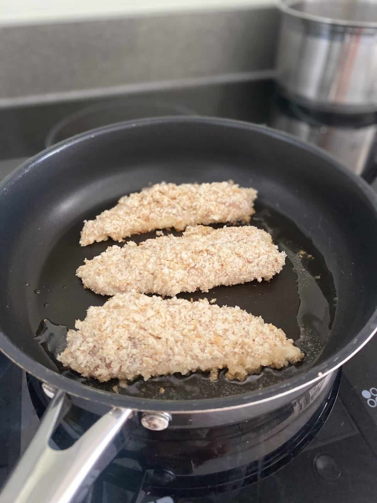 chicken goujons in pan cooking