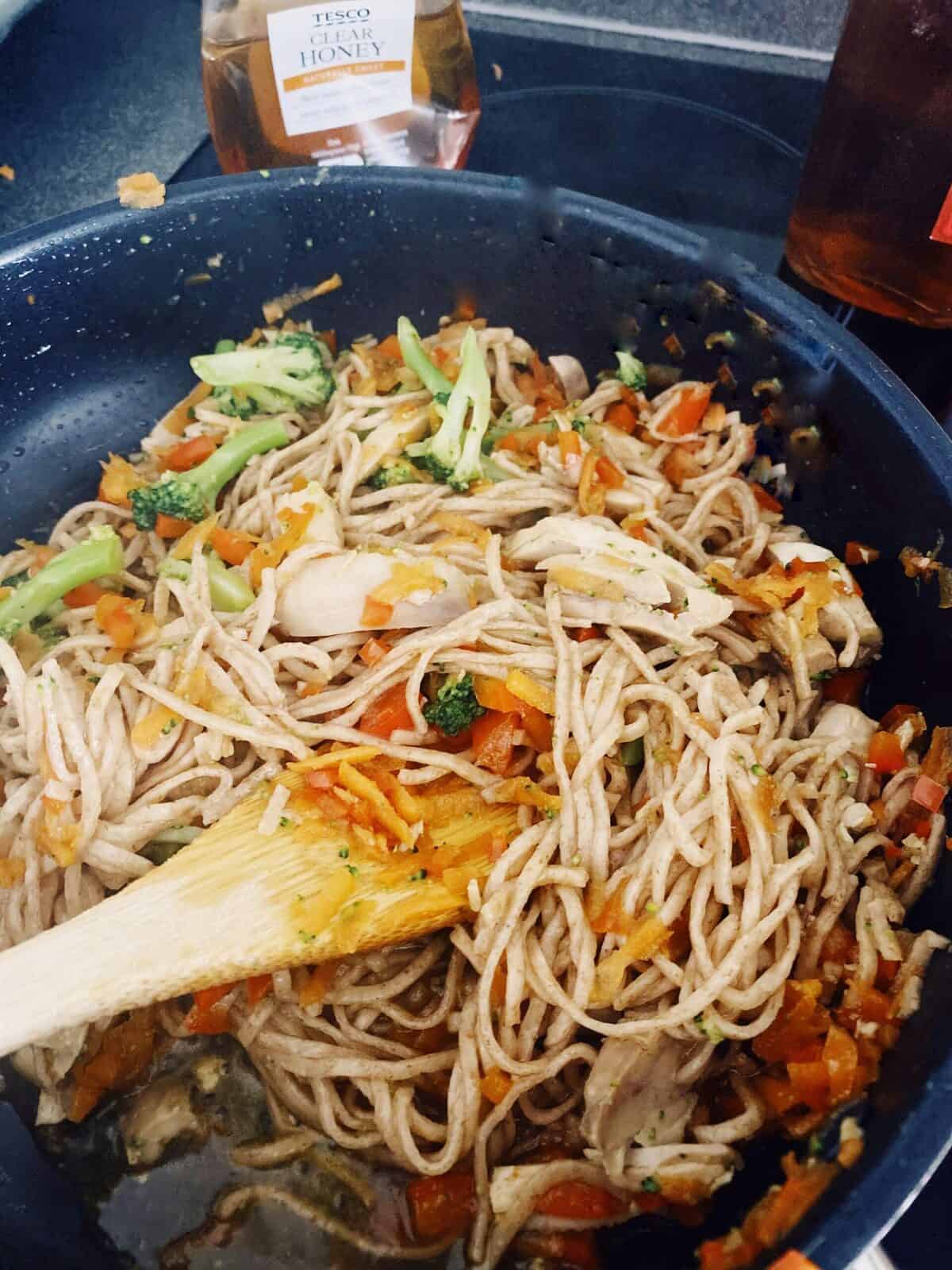 chicken noodles and carrots in frying pan