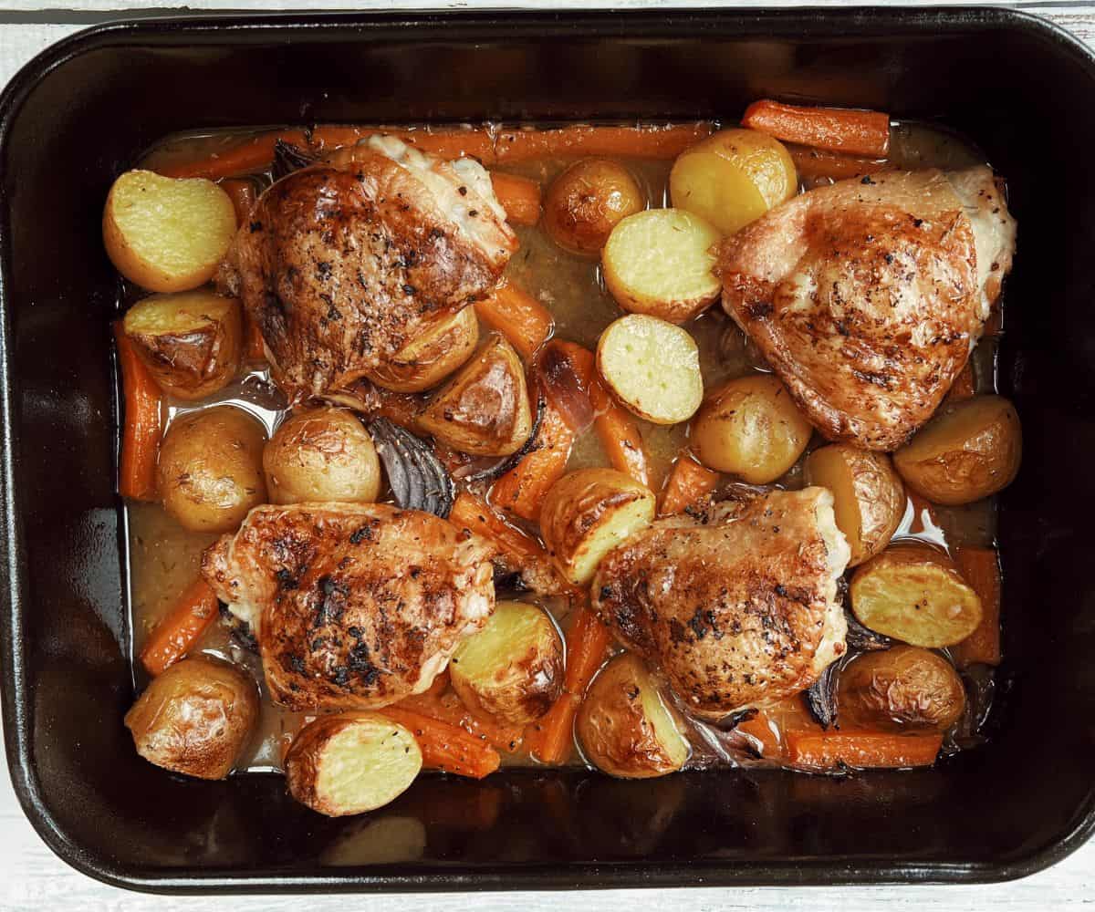 roasted chicken tray bake with potatoes and carrots in roasting dish