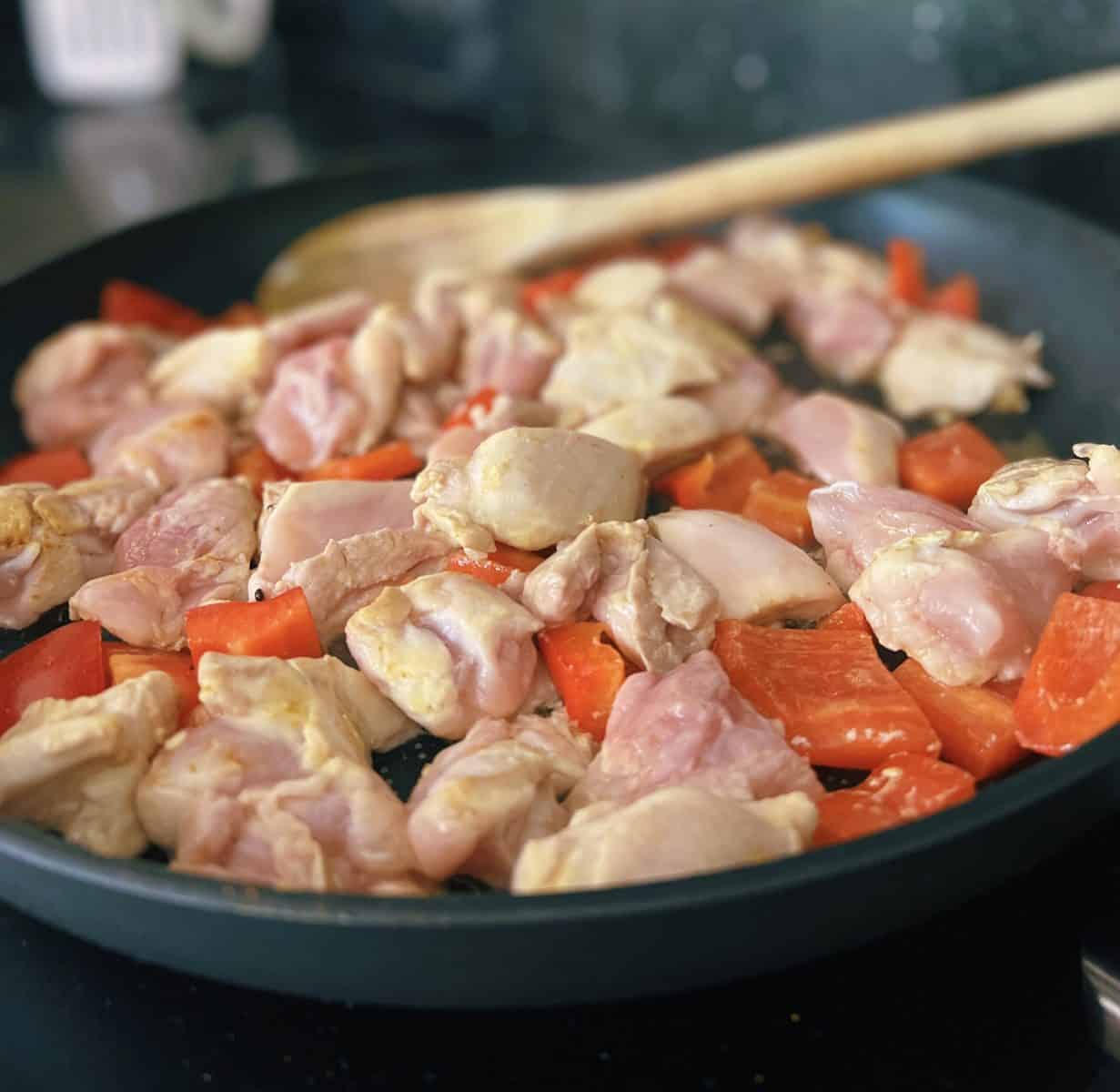 chicken, peppers and spices in a frying pan