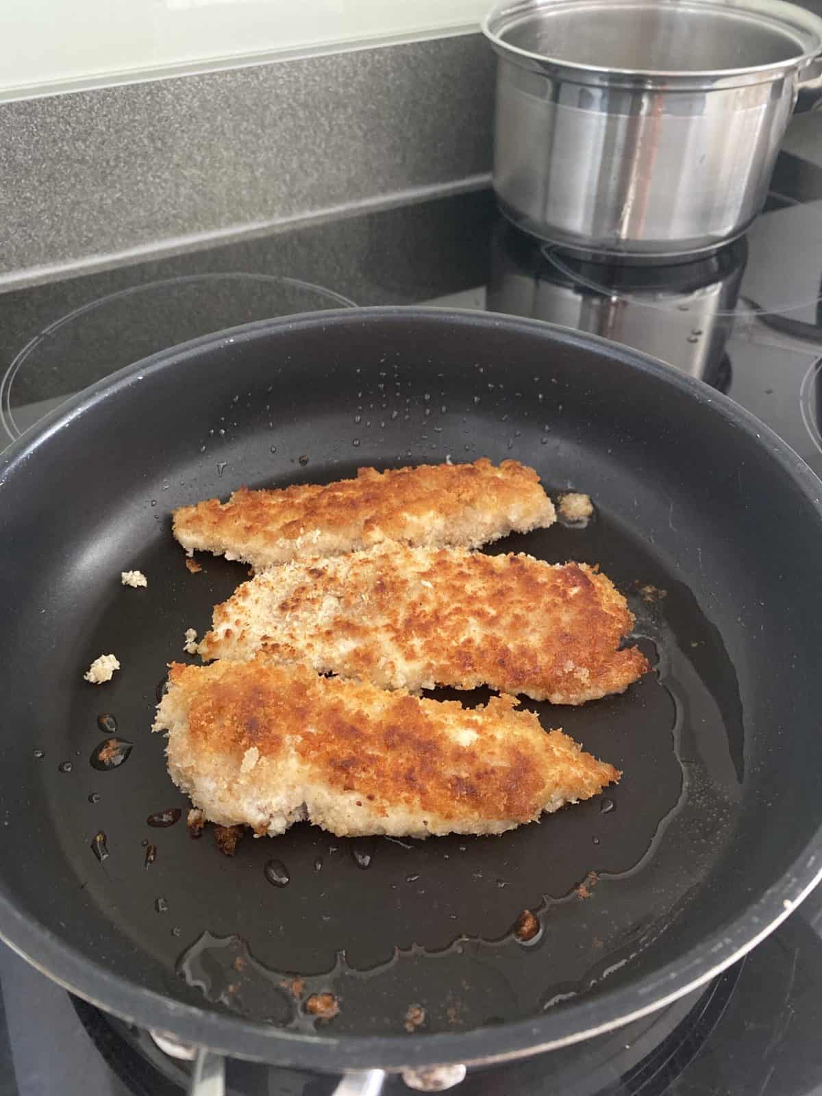 crispy chicken goujons in pan cooking