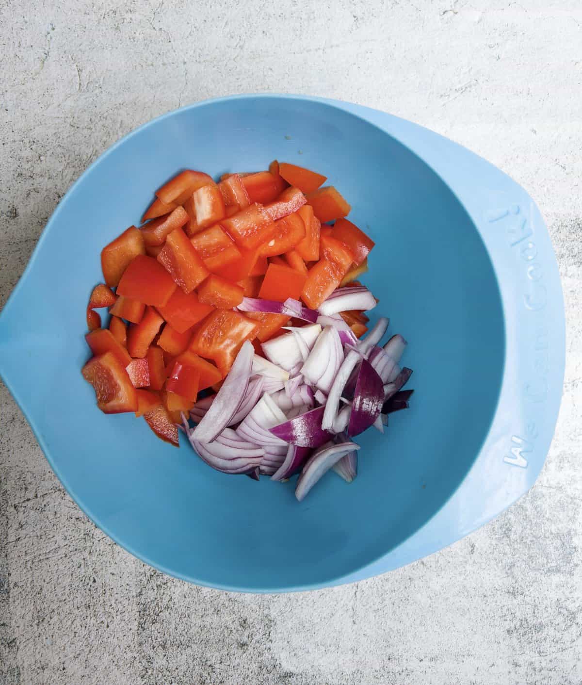 chopped red pepper and red onion in a blue bowl