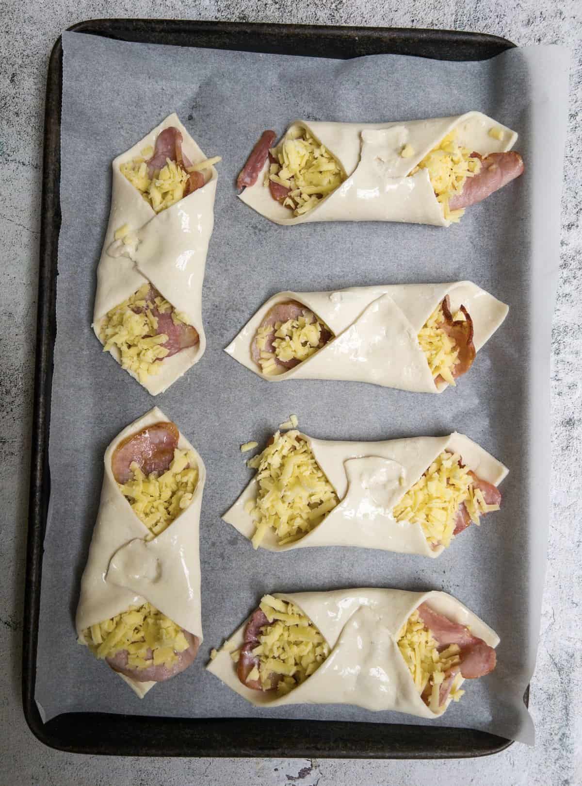 bacon and cheese turnovers on a baking tray uncooked.