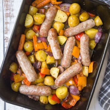 sausages and potatoes and peppers in a roasting dish