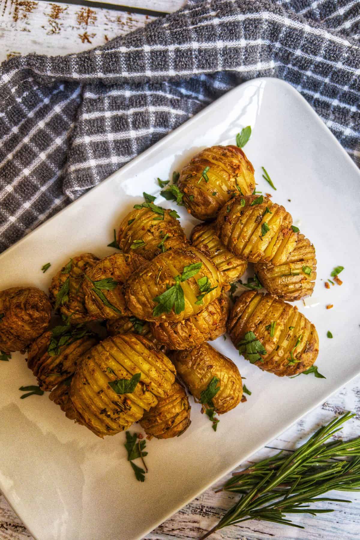 mini hasselback potatoes on a white plate garnished with parsley