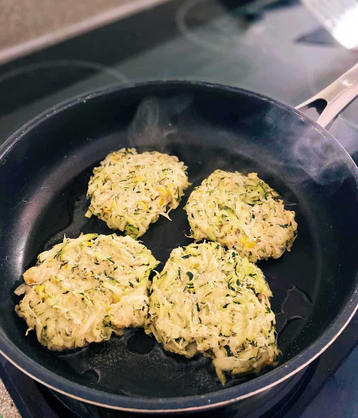 courgette & sweetcorn fritters frying in a pan