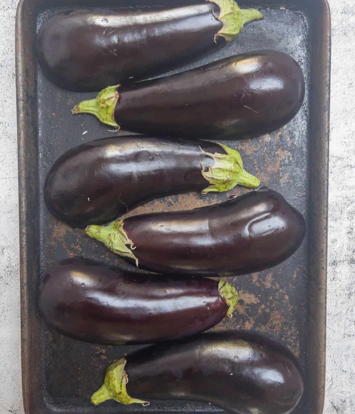 halved aubergines laid out on a roasting tray.