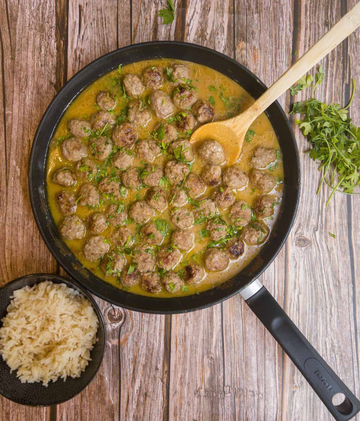 Swedish meatballs with gravy in a frying pan with a side of rice≥