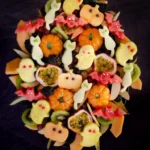 Halloween themed fruit salad with fruit including apple and melon cut into shapes with Halloween cookie cutters.