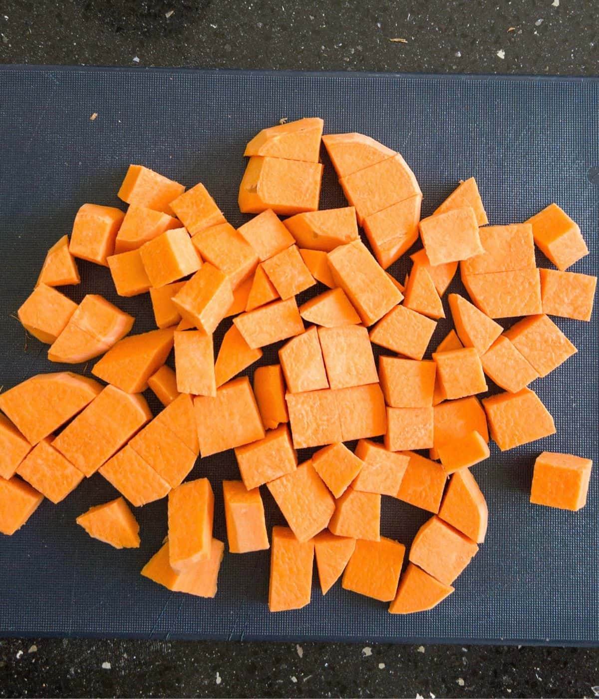 chopped chunks of sweet potato on a blue chopping board.