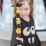 Fruit on a skewer with a bat decoration at the top being held by a child.