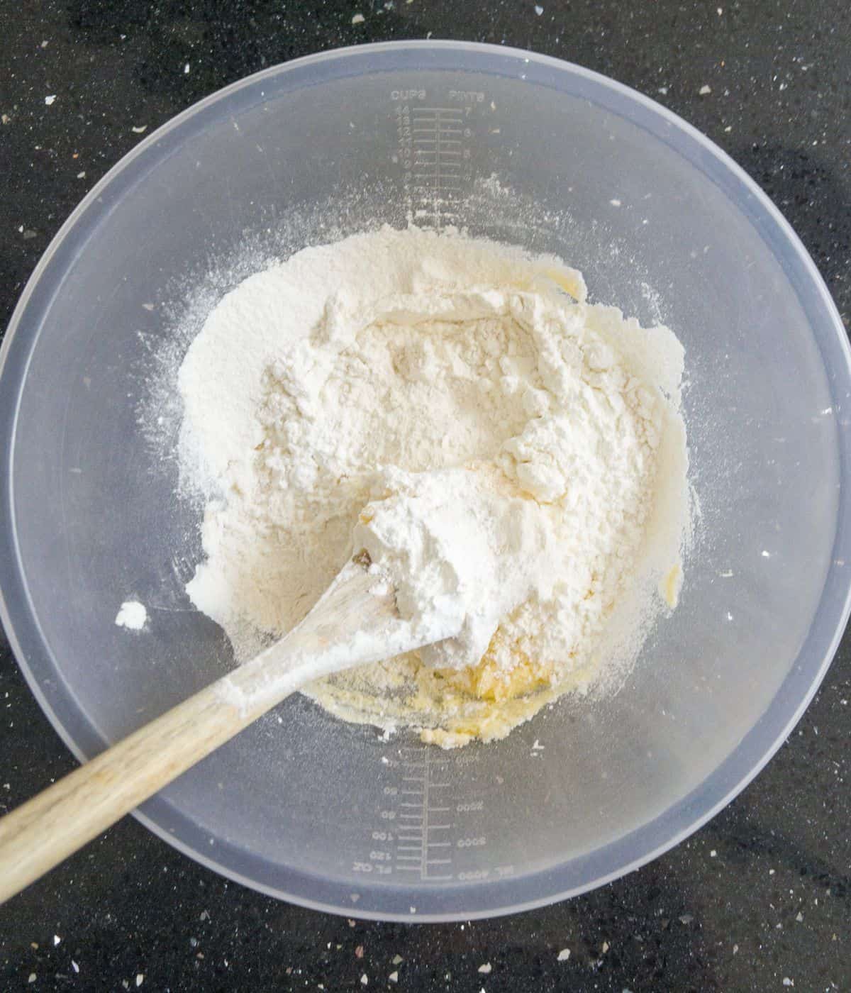 flour, sugar and butter in a mixing bowl with a wooden spoon.