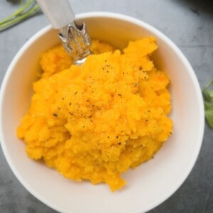 close up of swede and carrot mash in a white bowl.