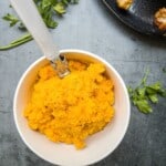 carrot and swede mash in a bowl with a spoon.
