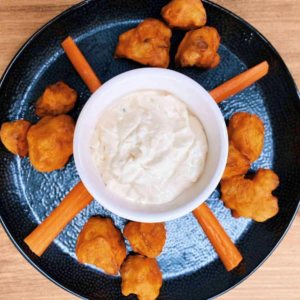 cauliflower bites on a plate with ranch dip and. carrots
