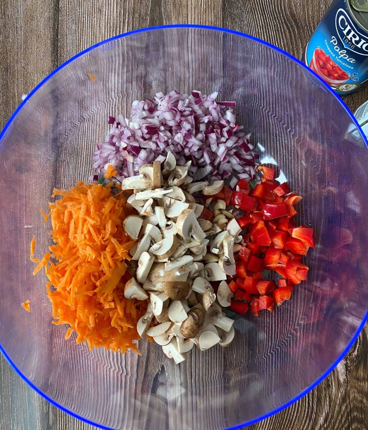 grated carrot, chopped pepper, red onion and mushrooms in a bowl.