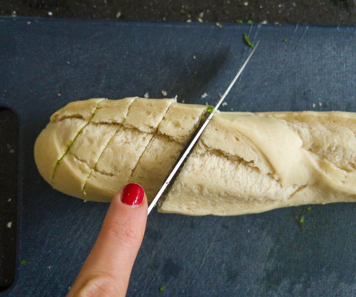 Baguette being chopped into slices with a knife.