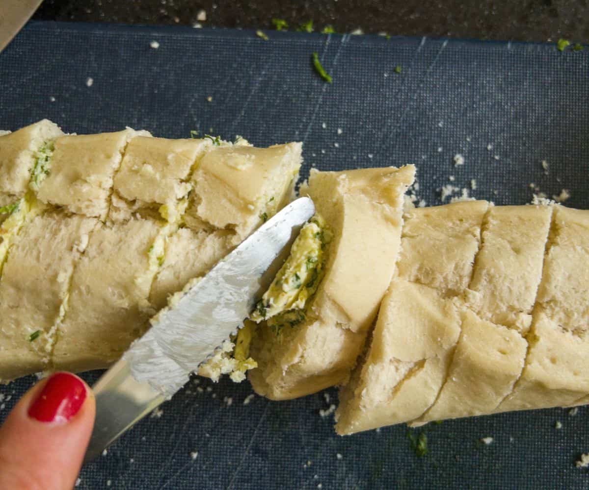 Garlic butter being spread into a baguette.