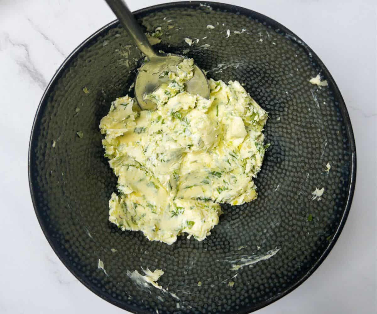 creamed butter mixed with garlic and parsley in a black bowl.