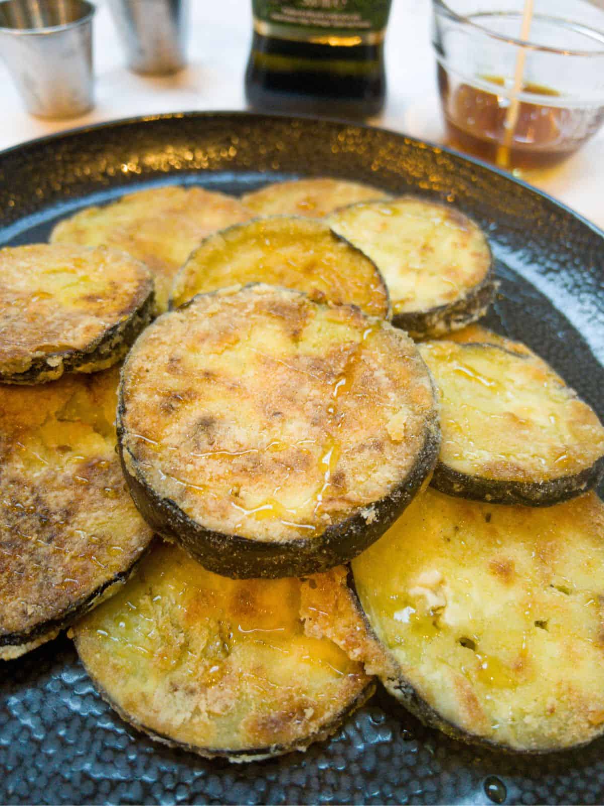 Close up of fried aubergine rounds on a plate.