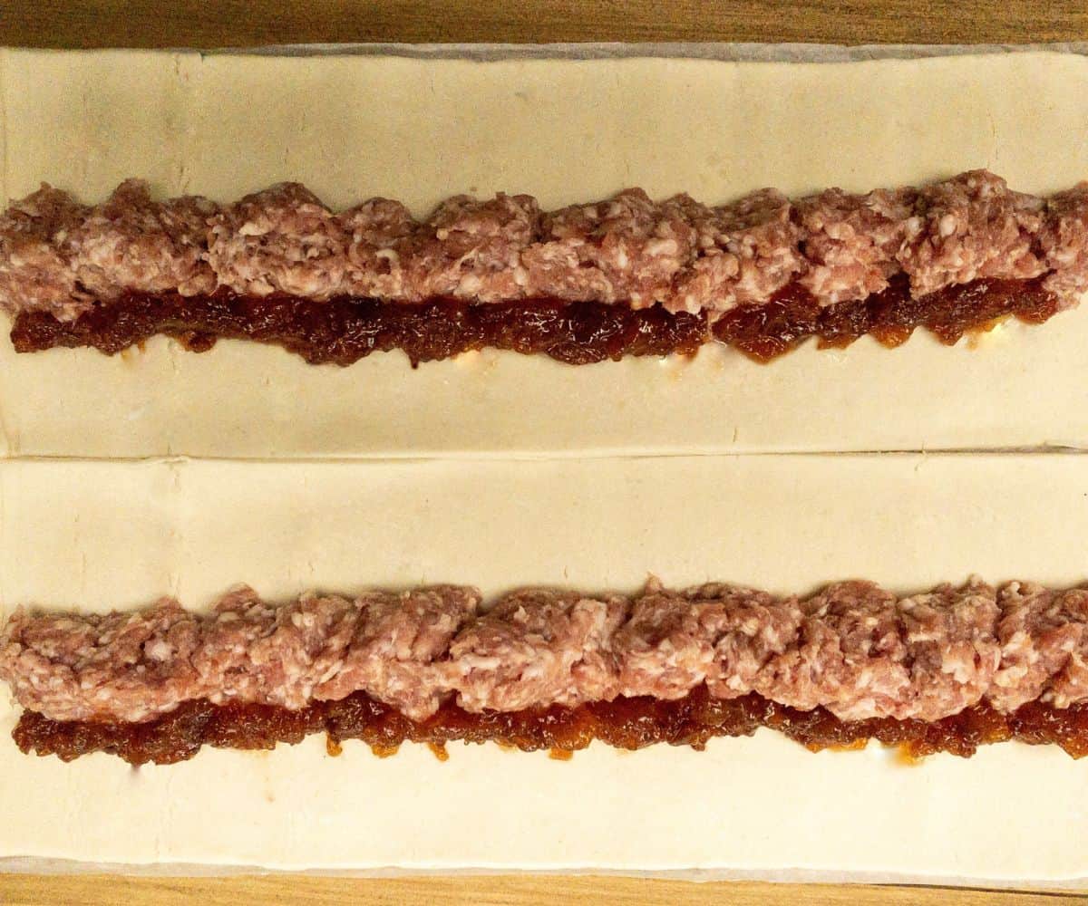 Sausage meat and chutney in a line in the middle of a puff pastry sheet.