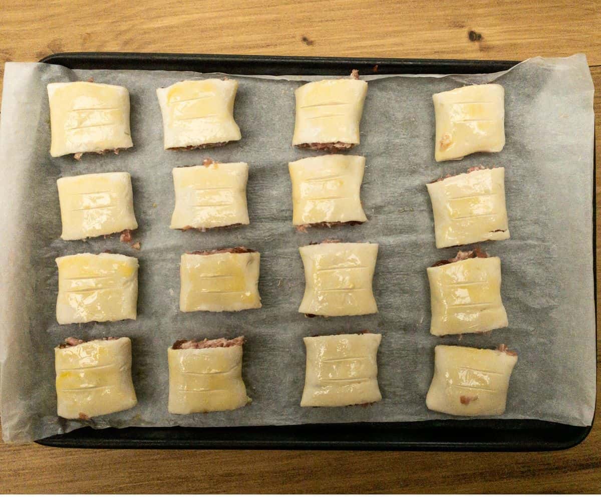 raw mini sausage rolls on a baking tray ready to go into the oven.