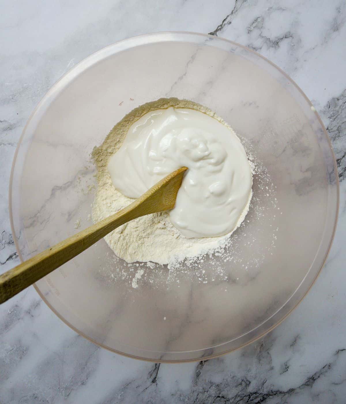 flour and yoghurt being mixed together in a bowl.