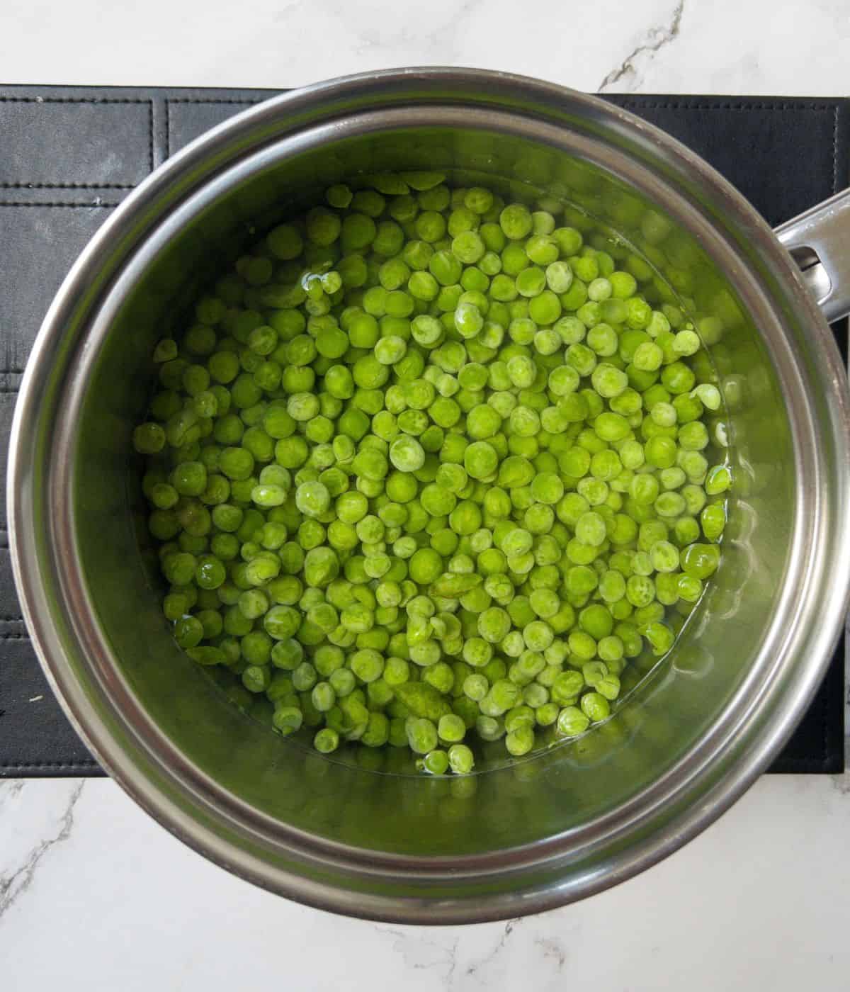 Peas in a saucepan with water.