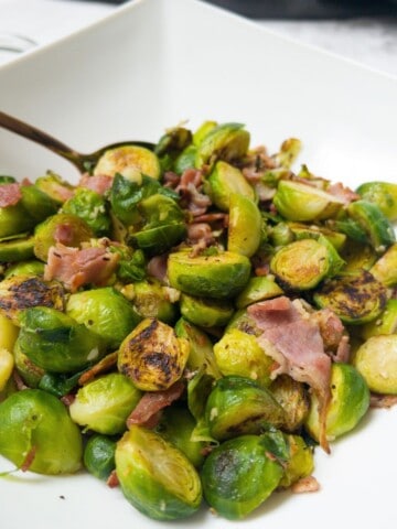 Brussel sprouts with bacon and garlic in a white bowl.