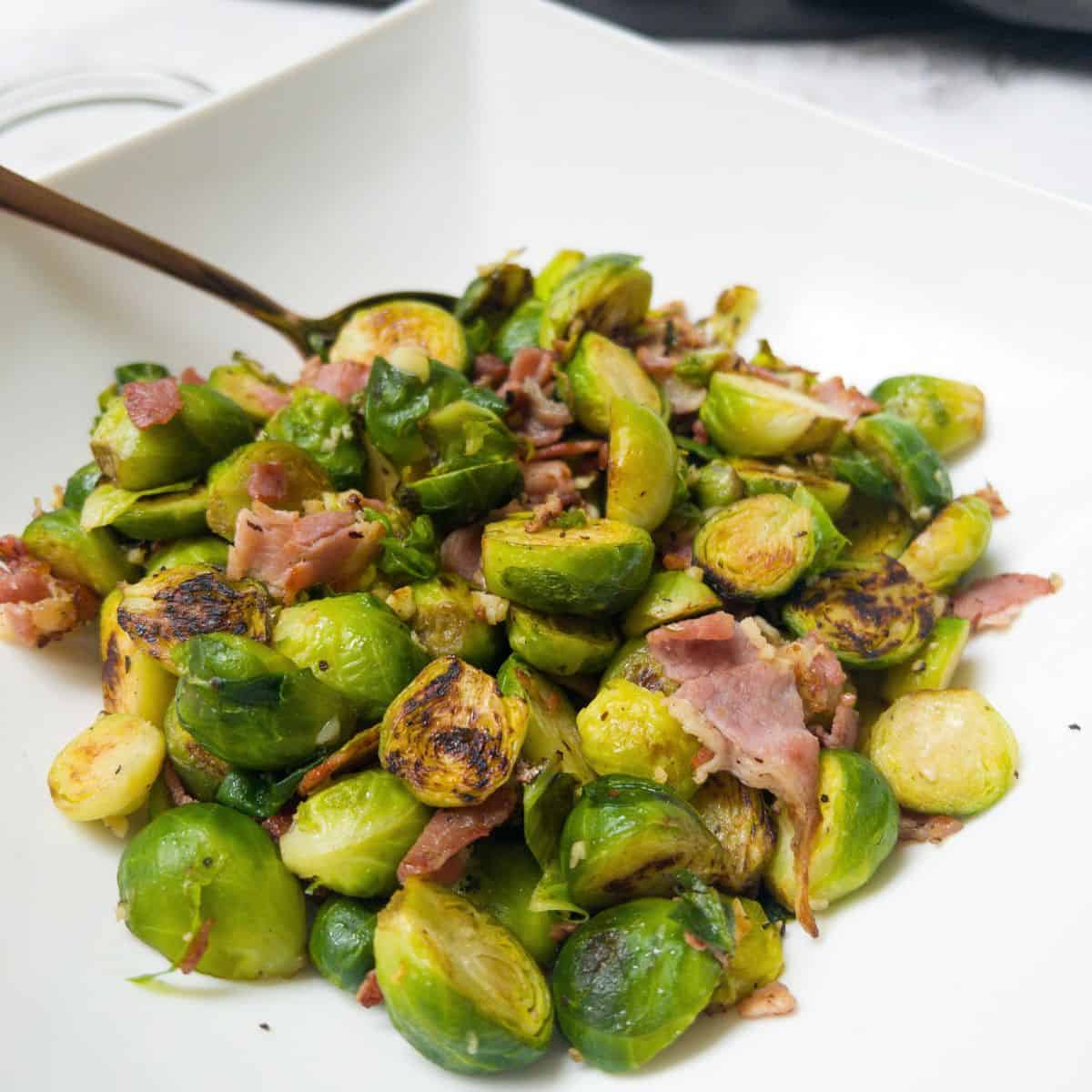 Brussel sprouts with bacon and garlic in a white bowl.