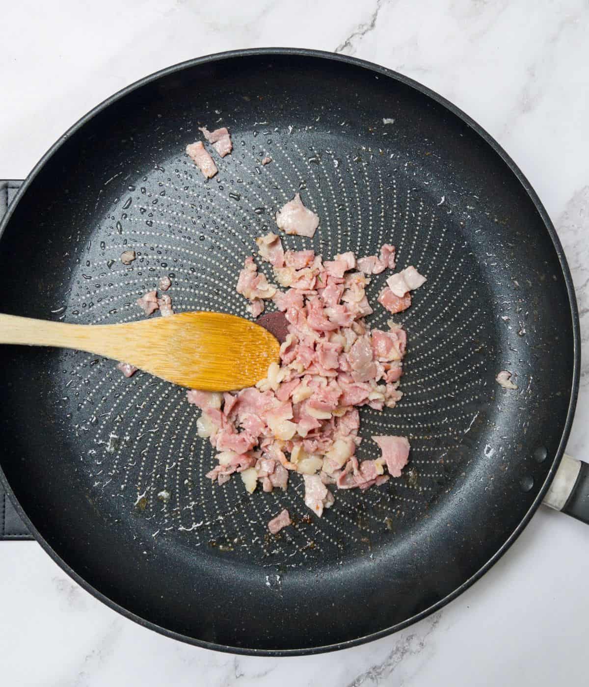 Bacon frying in a frying pan.