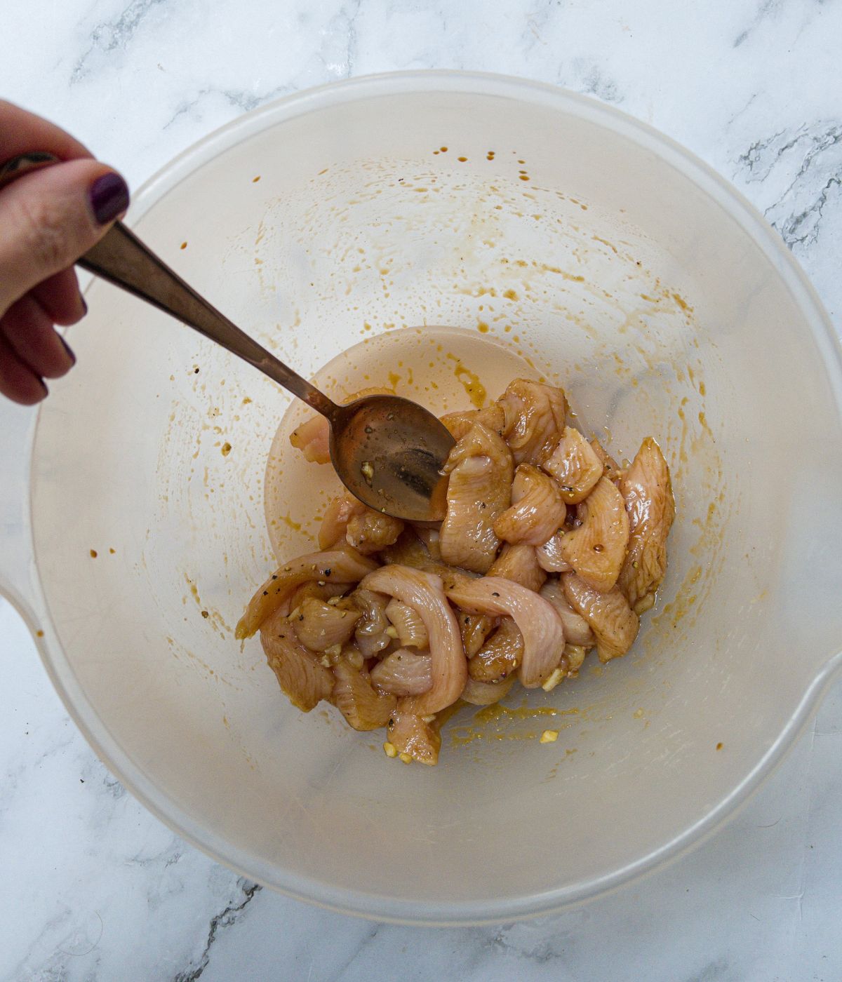 Chicken pieces marinated in soy sauce and ginger, being mixed in a bowl.