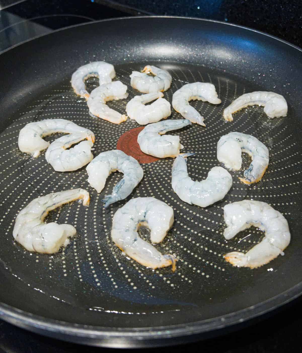 Raw jumbo king prawns frying in a pan.