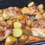 chicken potatoes, carrots and red onion with a sauce in a baking tray.