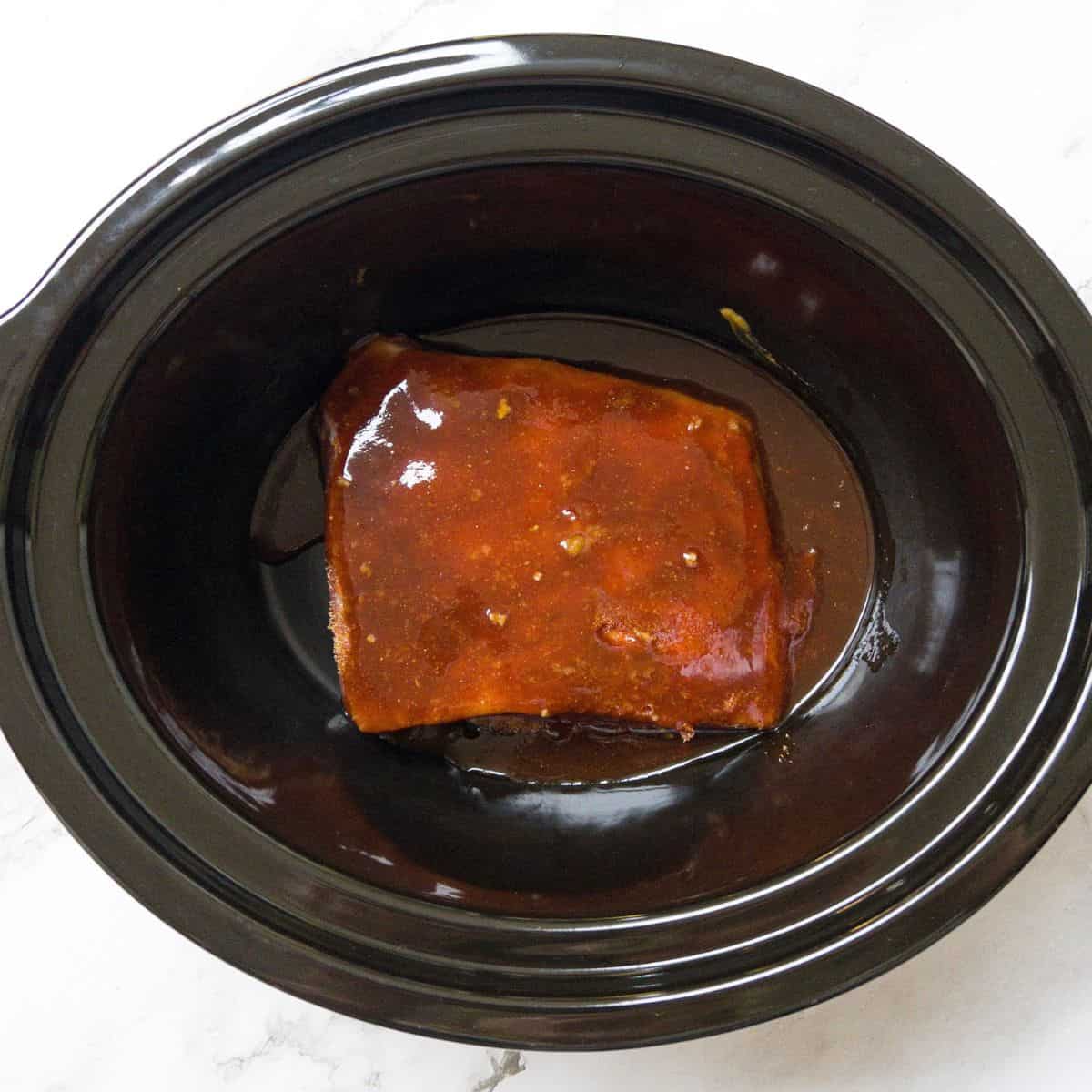 beef brisket with bbq sauce in a slow cooker.