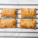 Four cooked rectangle apple turnovers on a cooling rack.