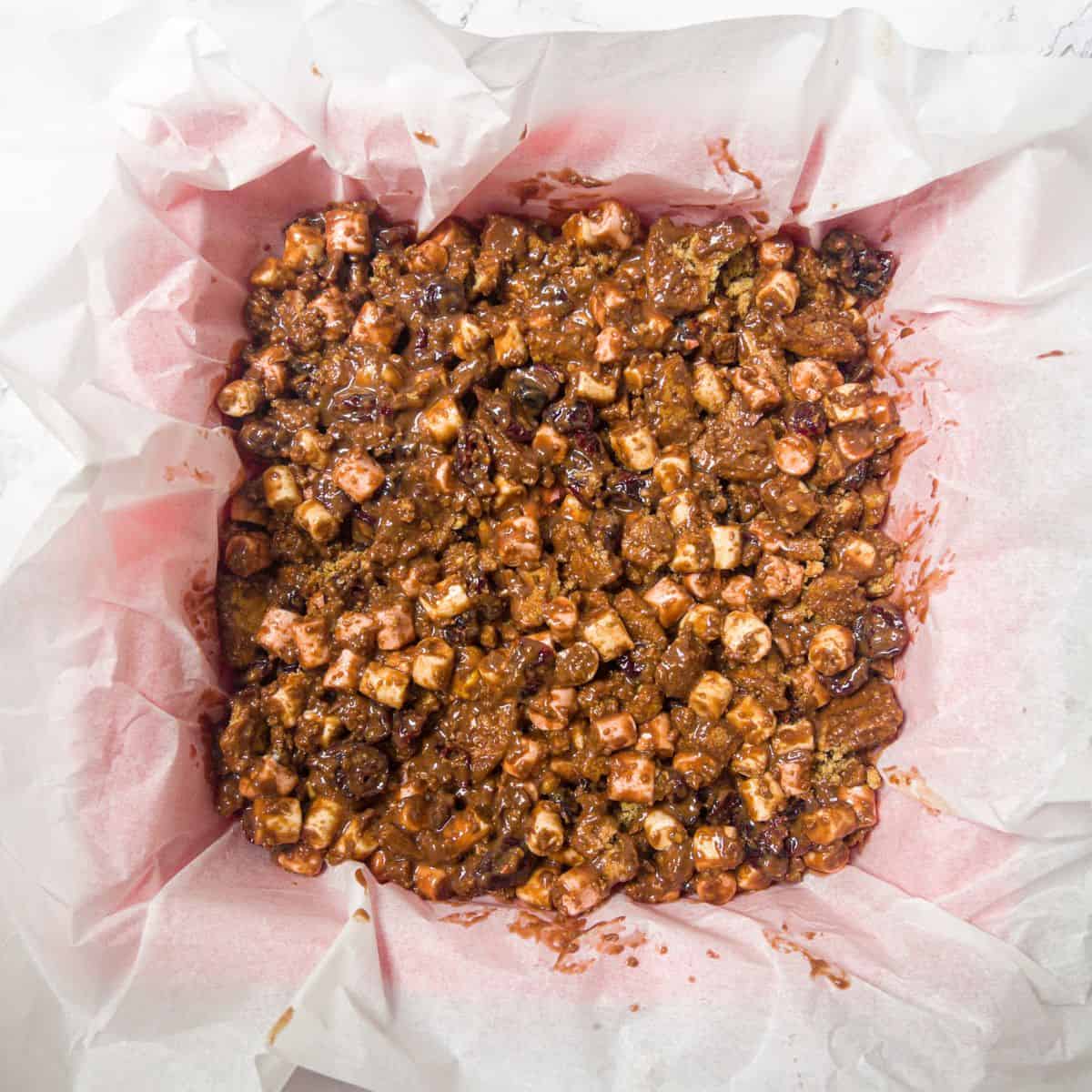 Un-set rocky road mix in a greaseproof paper lined baking tin.