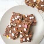 Five squares of rocky roads on a plate with a couple of squares in the background.