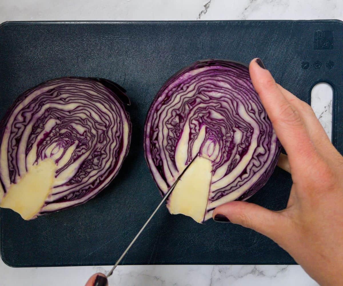 The core being taken out of a red cabbage with a knife.