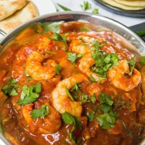 Prawn balti garnished with coriander with popadums in the background.