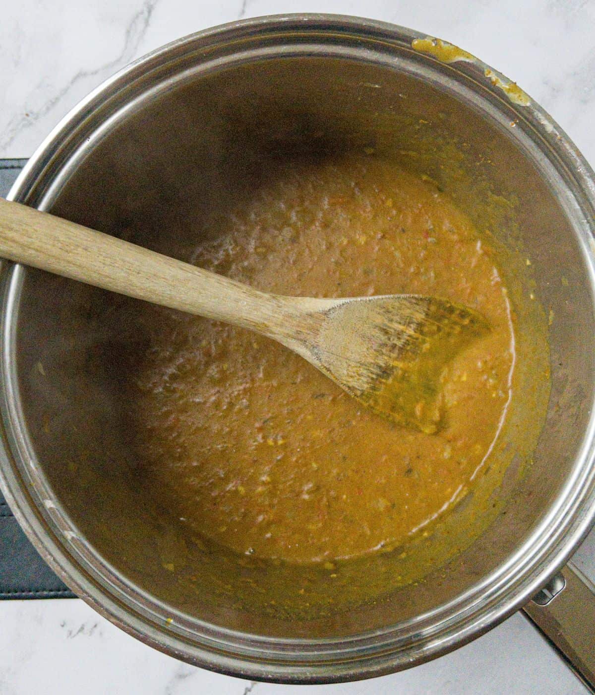 Katsu curry sauce in a saucepan with a wooden spoon.