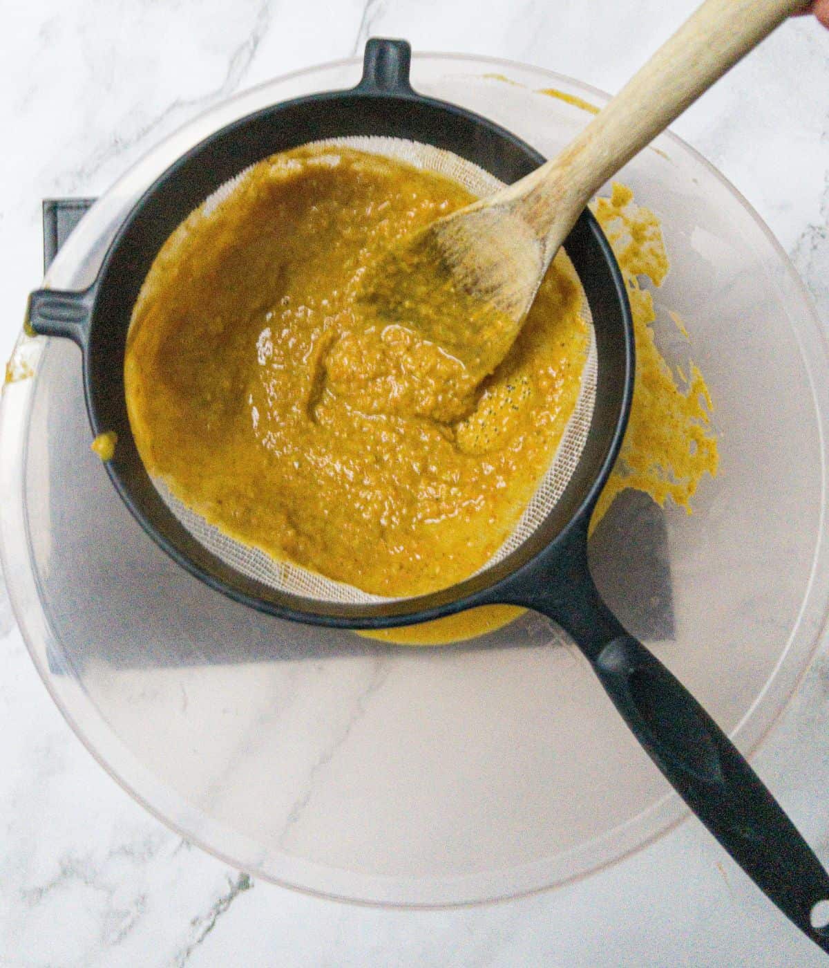 Katsu curry sauce being put through a sieve into a bowl to thin it.