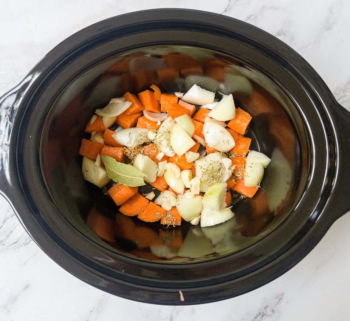 Carrots, onion, rosemary & garlic in a slow cooker.