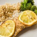 Trout fillet garnished with lemon on a plate with rice and broccoli.