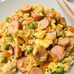 Hot dog fried rice with egg and peas on a plate.