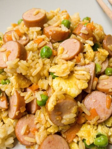 Hot dog fried rice with egg and peas on a plate.
