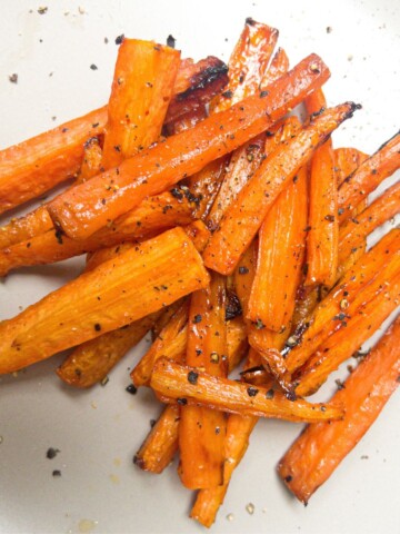 Cooked carrot sticks sprinkled with black pepper.